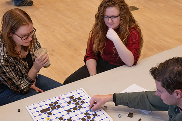Three first-year students are playing a handmade board game.
