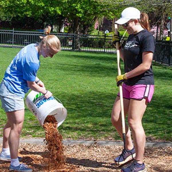 Two students working outdoors in a park setting.