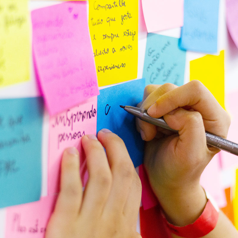 Hands writing notes on colorful Post-its