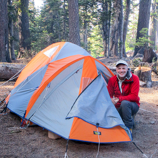 Whitman College instructor posing next to a tent.