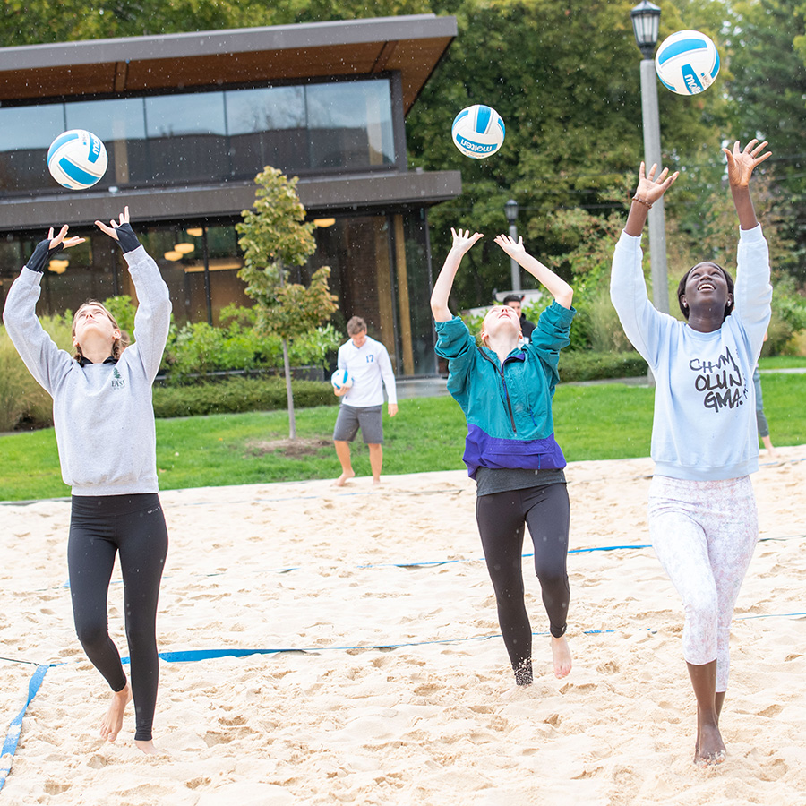 Whitman students practicing volleyball in outdoor sand courts. 