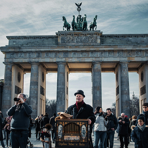 Elderly man standing infront of the Holocaust Memorial in Berlin, playing the barrel organ.