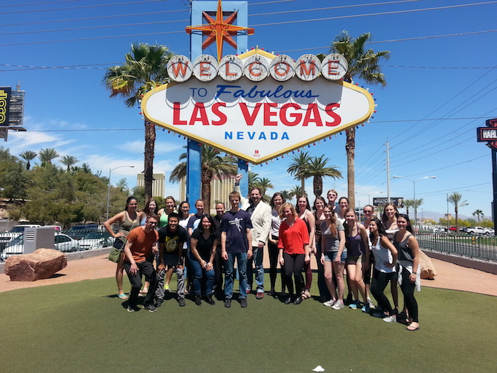 Group of students stand around Las Vegas welcome sign