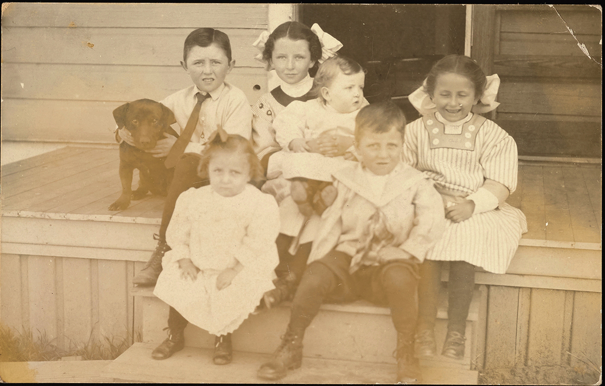 Old photograph of kids sitting on a porch.