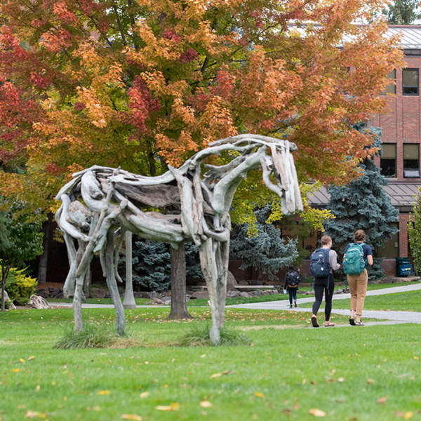 Students walking on Whitman College Ankeny Field with the Styx sculpture