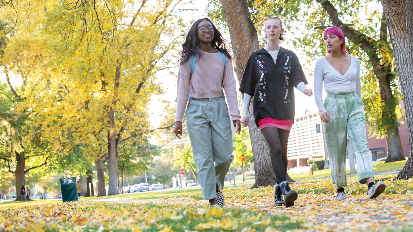 Whitman student walking on campus with fall leaves