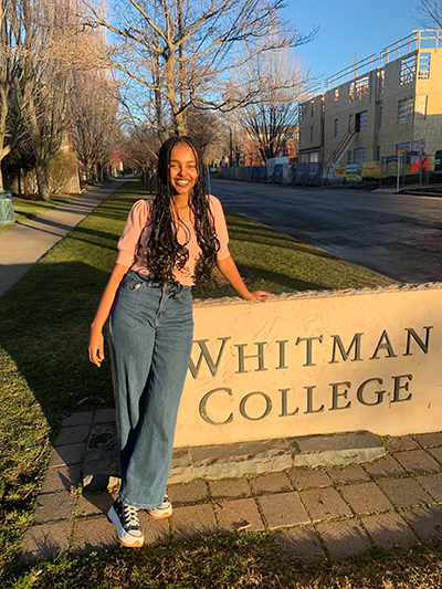 Ruth Chane standing next to a Whitmsn College sign.