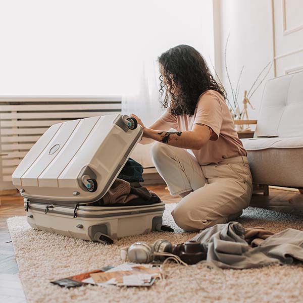 Student packing a suitcase on the floor.