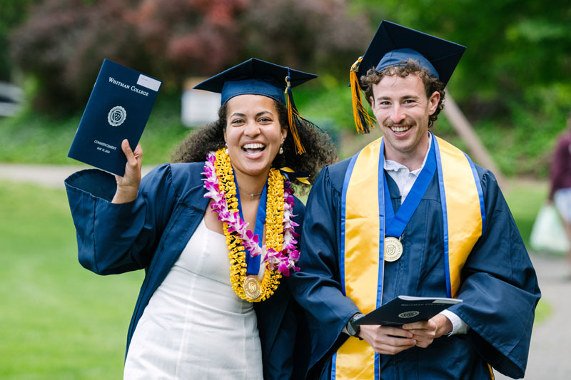 Two Whitman students in commencement regalia.