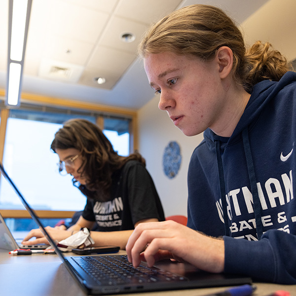 Whitman College Debate & Forensics team working behind a computer.