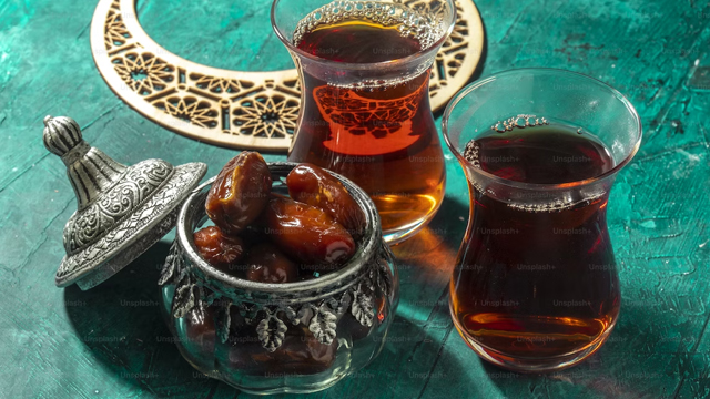 a glass bowl of dates with two glass mugs of tea
