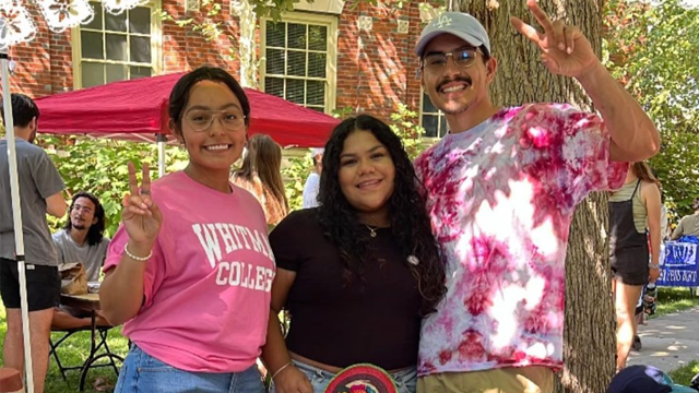 Three students pose for a picture, outdoors at the student activities fair.