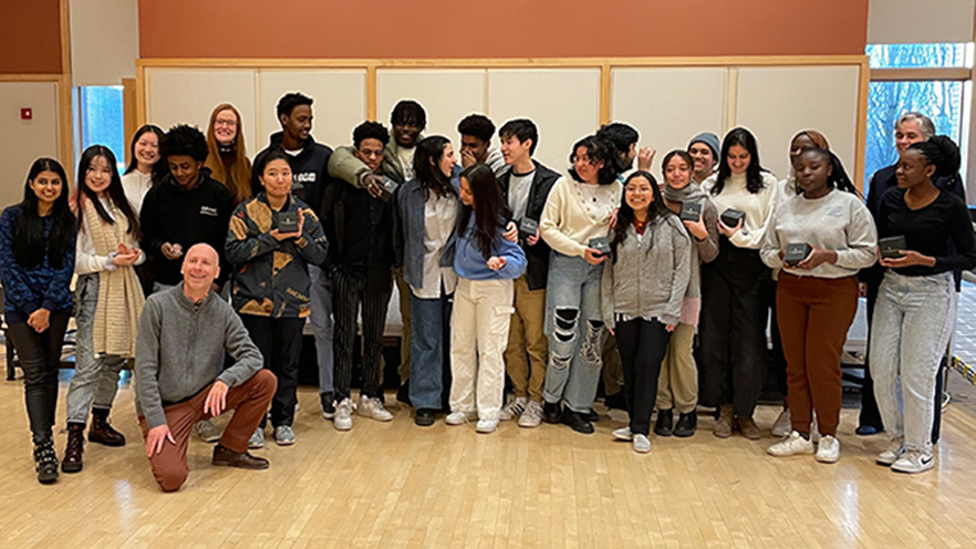 A group of students, many holding small glass globes.