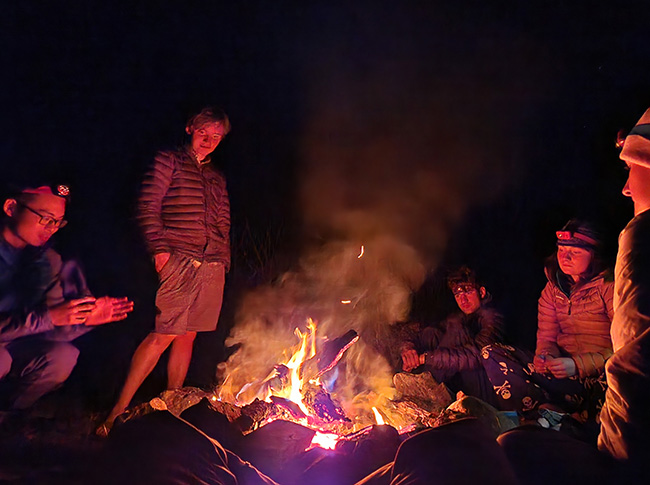 A group of Whitman students huddled around a fire in a overnight outing.