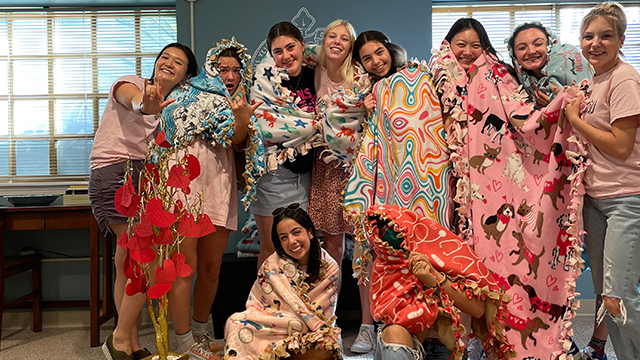 A group of sorority members, each wrapped in a pink blanket.