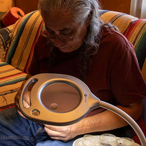 Marcus Amerman works on beading on his couch at his home.