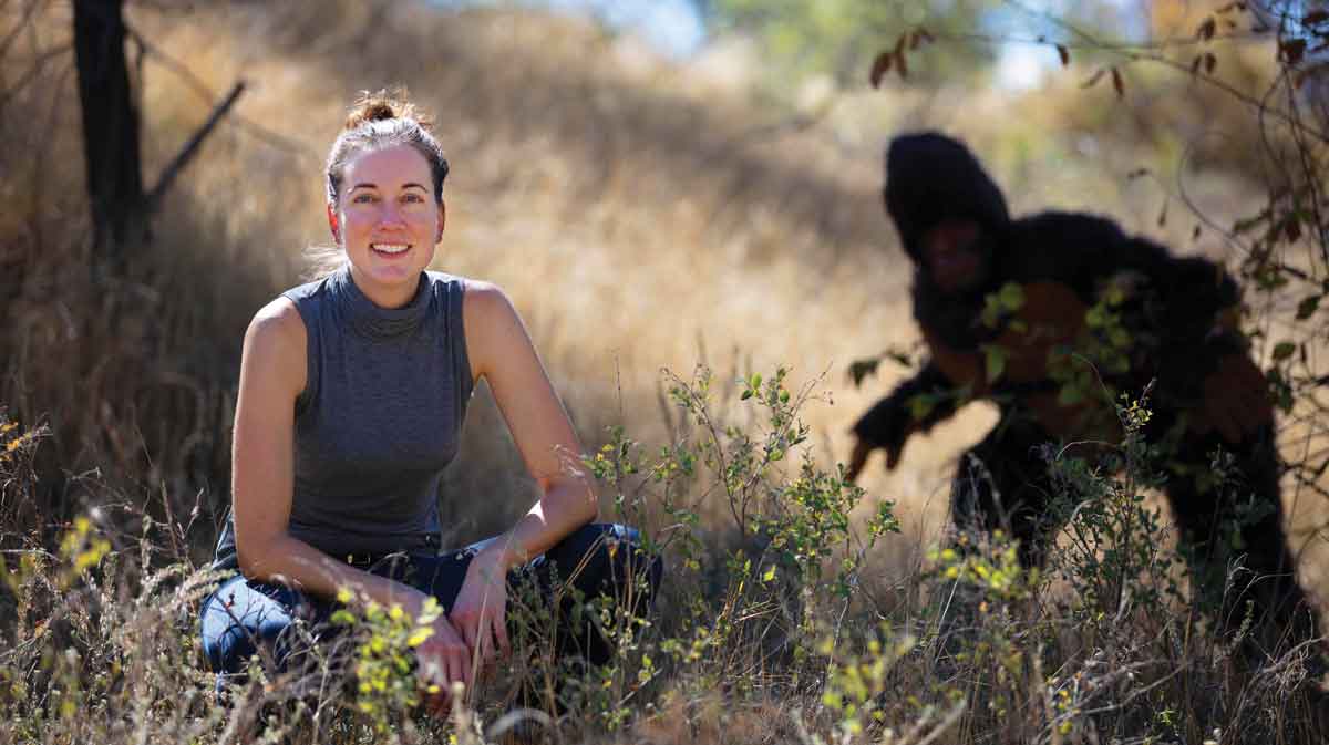 Laura Krantz in a field with Bigfoot in the background