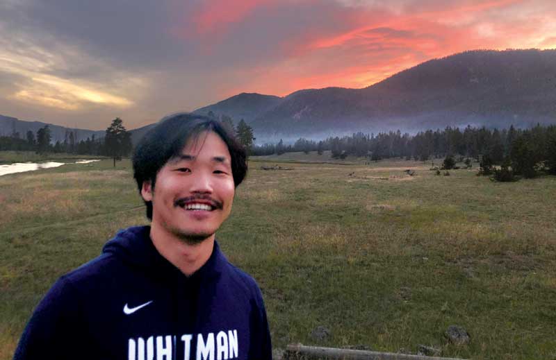 Eric Lim outdoors with a sunset behind the mountains.