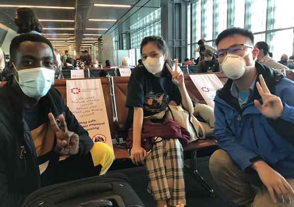 Students at the airport giving the peace hand sign.