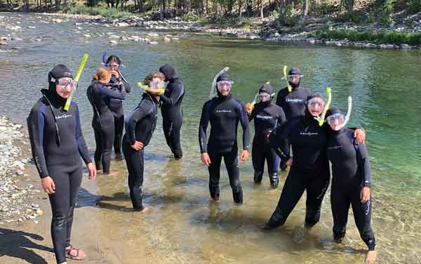 Students wearing wetsuits standing on the bank of the Methow River.