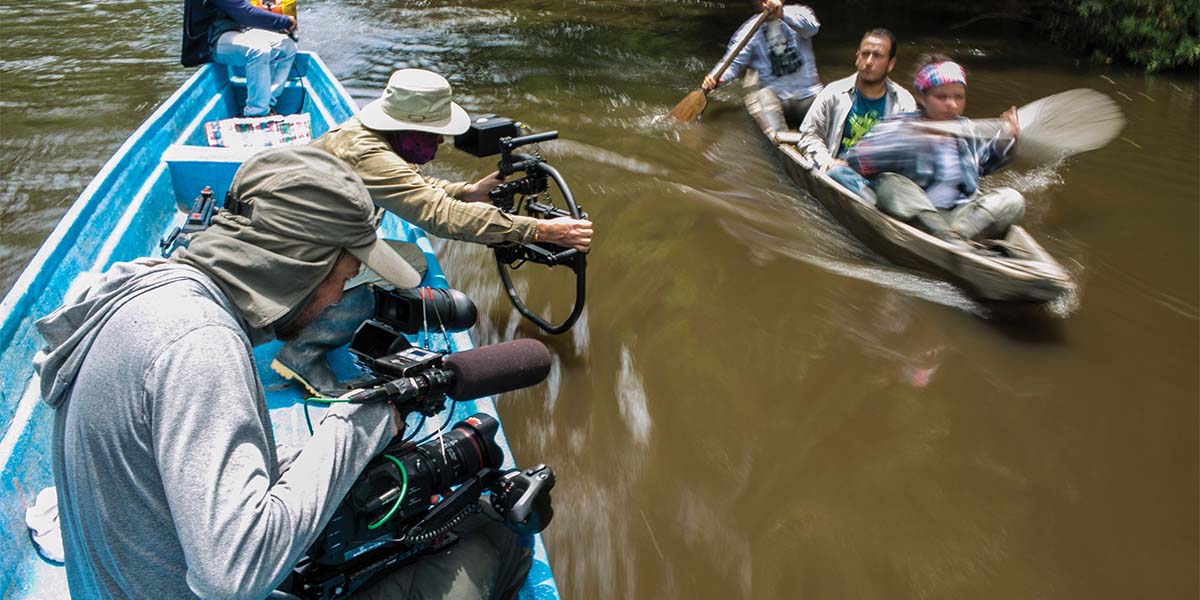 Rick Smith filming primate researchers on a river.