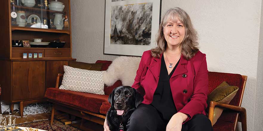 Michelle Janning sitting inside her home with her dog by her side.