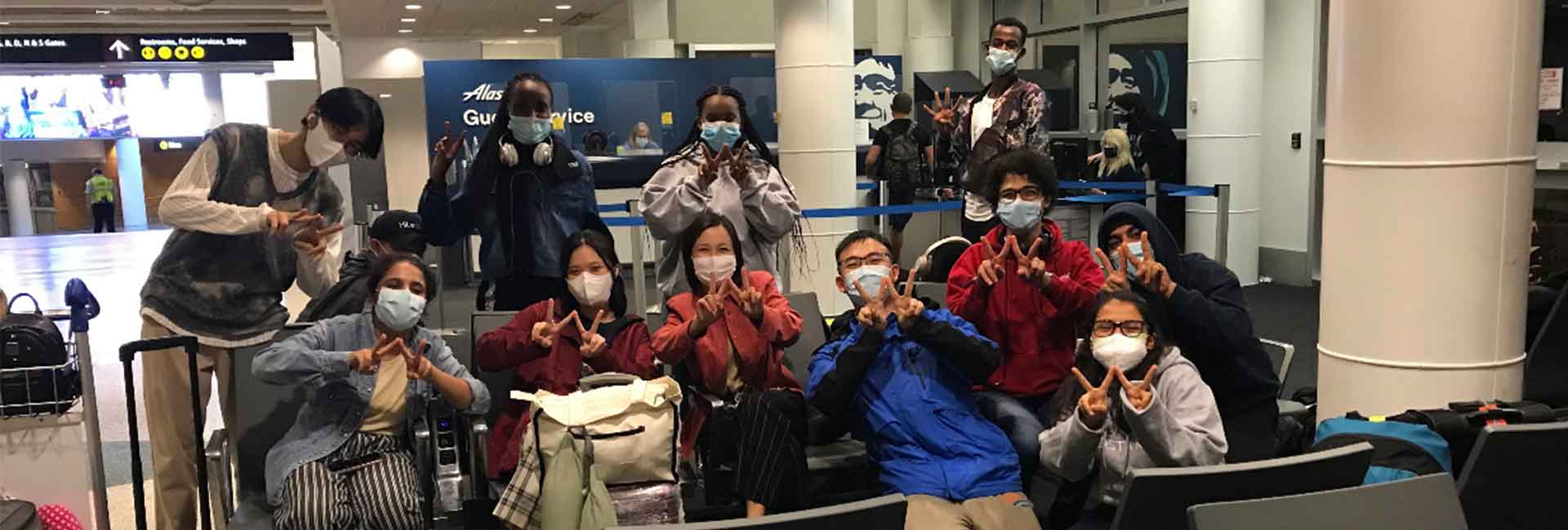 Large group pf students at the airport posing for the camera.