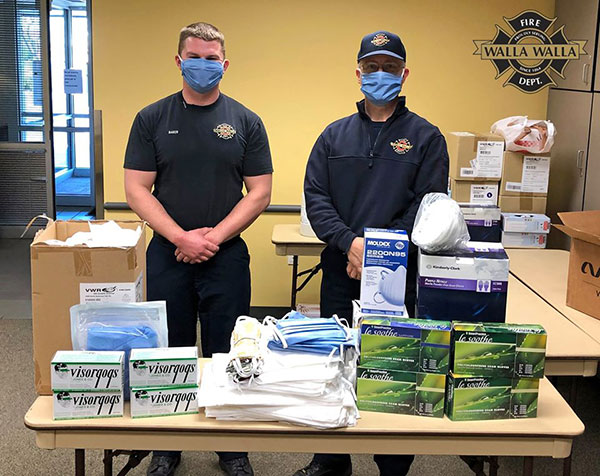 Firefighter/medic Eric Baker and firefighter/EMT Tim Thompson stand with supplies donated to the Walla Walla Fire Department by Whitman College and other community groups and individuals.