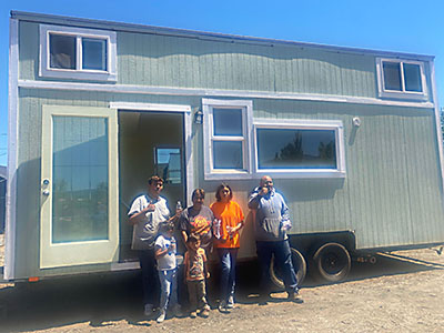 The new owners standing in front of the tiny house.