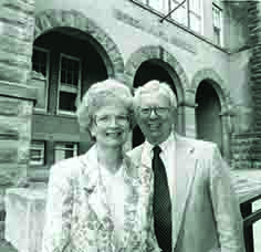 black and white photo of Tom and Nannette Edwards standing outside a stone building