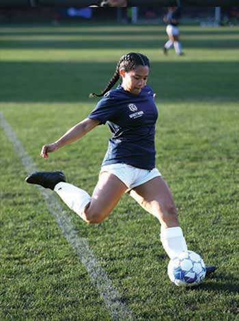 Whitman college soccer player kicking the ball