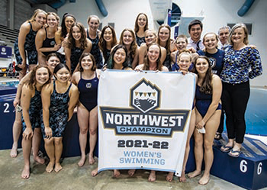 Whitman college's swim team holding a championship banner
