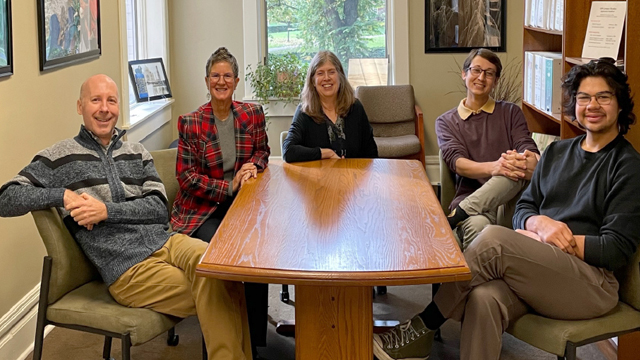 Five staff members sit around a table in an office setting. From left to right: Greg Lecki, Laura L. Cummings, Susan Holme, Nadir Ovcina, Ozzie Rodriguez.