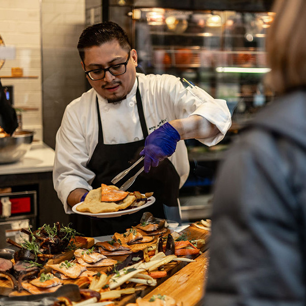 A food service worker putting food on a plate 