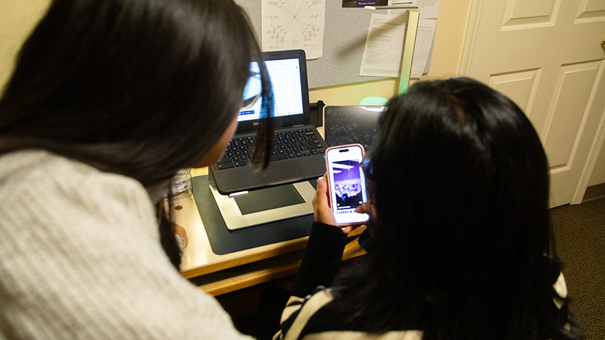 Abeer and Rosa looking at a phone screen.