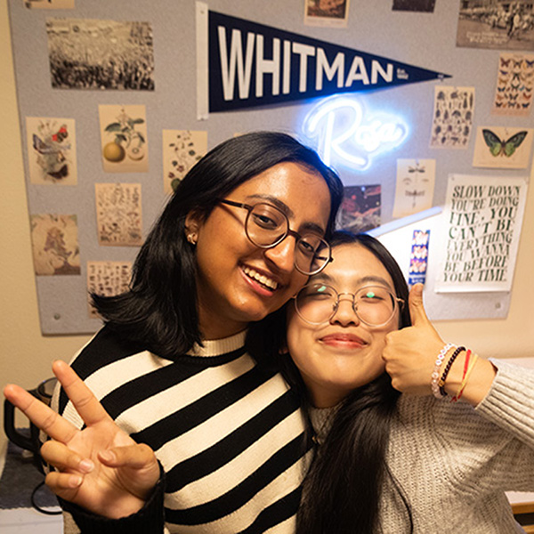 Abeer and Rosa posing in front of a pinboard.