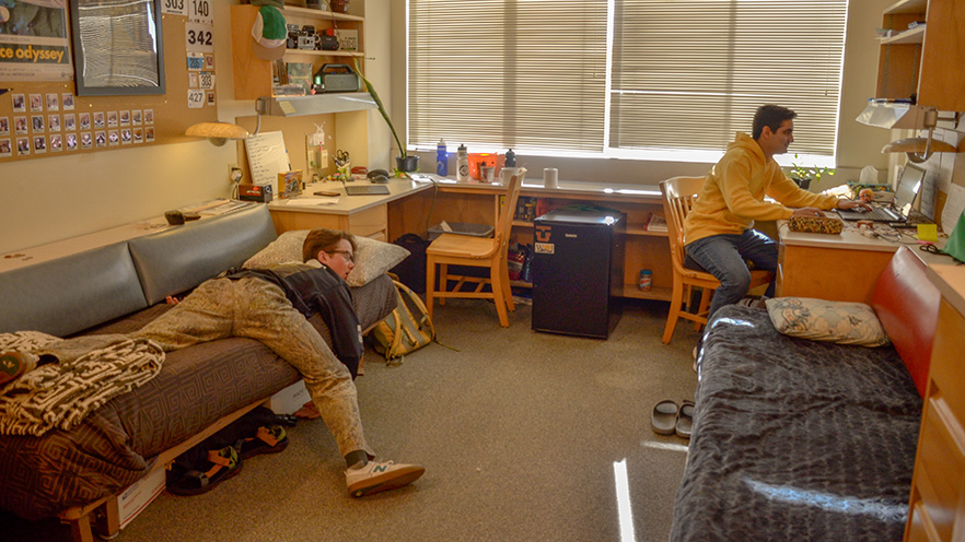 Erfan working on his desk while Griffin is asleep laid out on his bed.