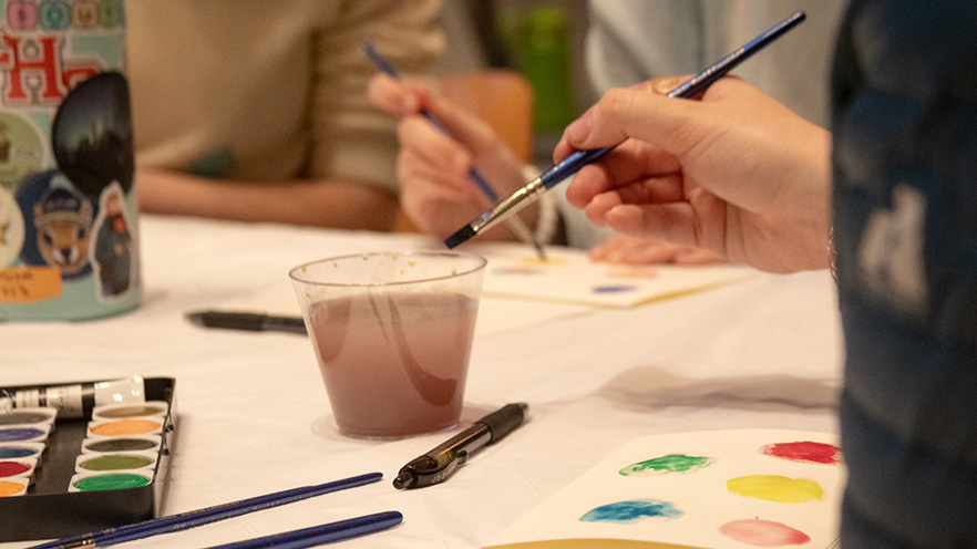 A brush water colors and a cup of water mixed with paint.