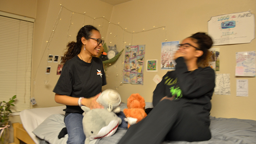 Zizia and Layla laughing on the bed.