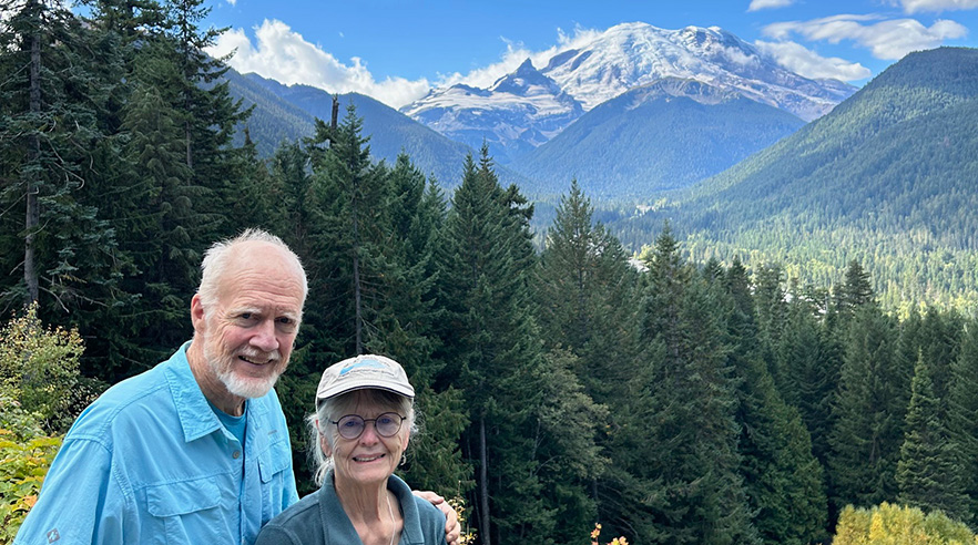 Bob and Clare Carson posing with Mt. Rainer behind them.