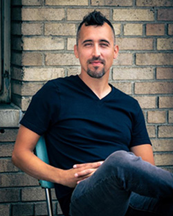 Noé Álvarez sitting in front of a brick wall