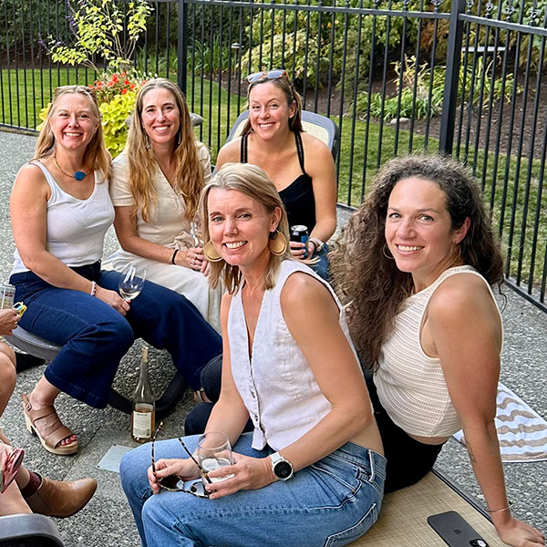 Five women sitting on deck chairs by a pool