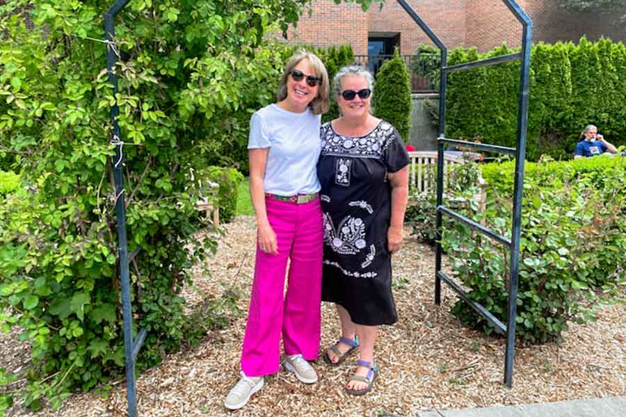 Molly McBranch '84 (left) and Chris Beard '84 (left) standing in a garden outside Maxey Hall at Whitman College.