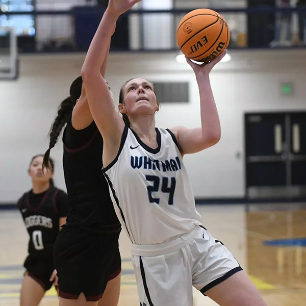 Korin Baker ’25 reaches up with a basketball in front of an opposing player