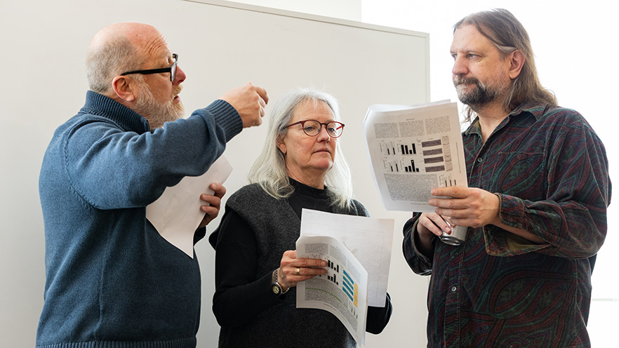 Three professors standing in a group in discussion