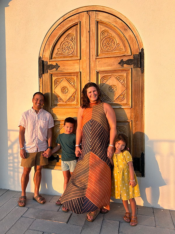 Two adults and two children standing in front of a carved wooden door