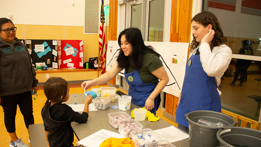 Whitman College students helping a child with a science experiment.