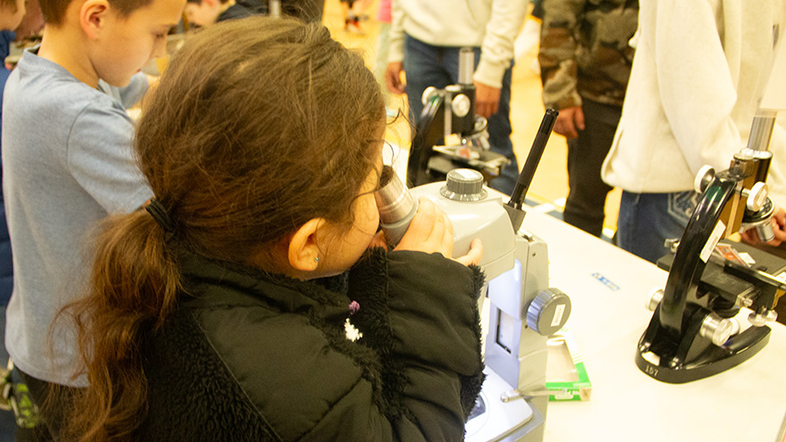 A child at Whitman Science Night looking through a microscope.