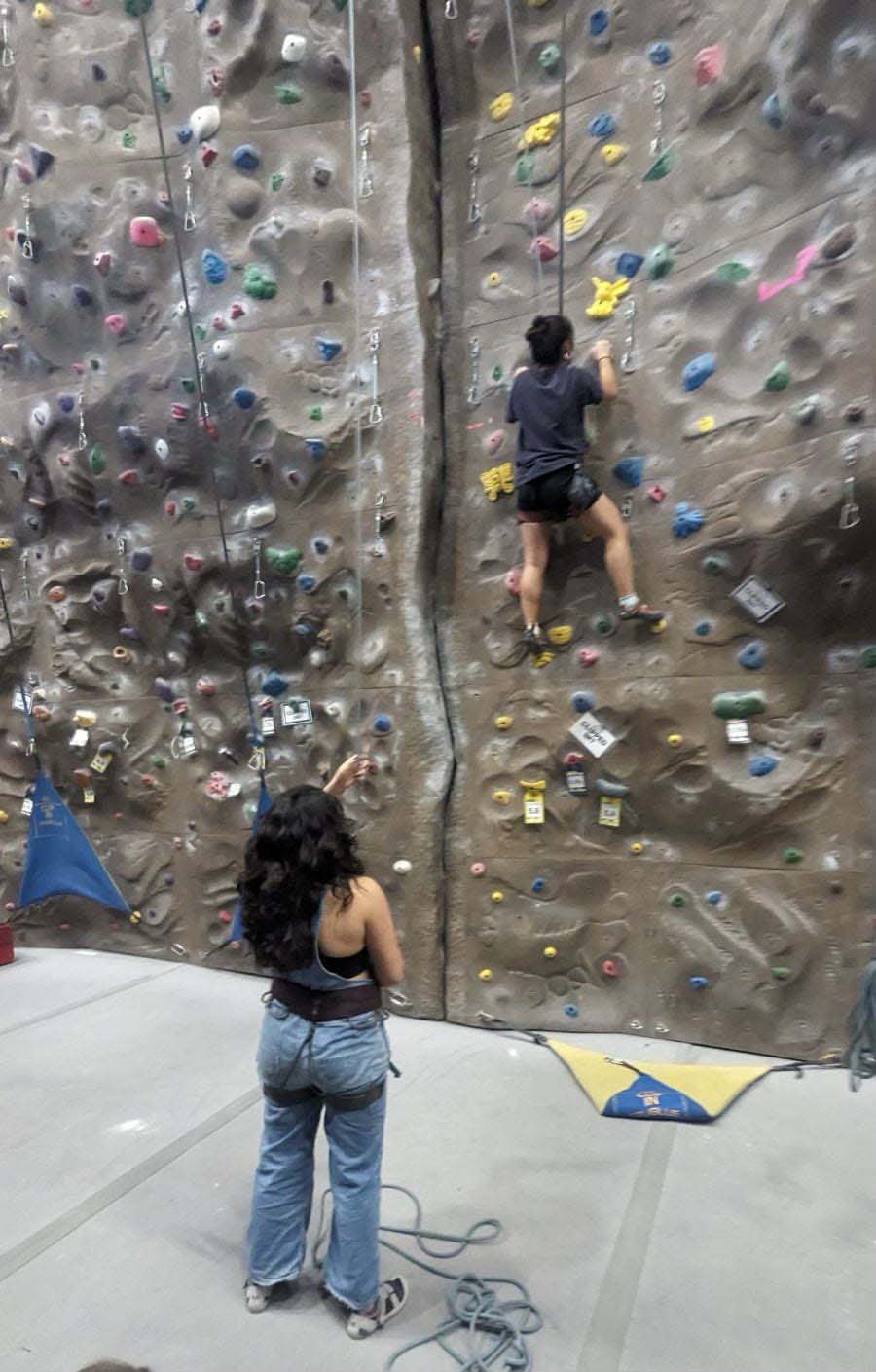 Rock climber watching another on the indoor climbing wall.